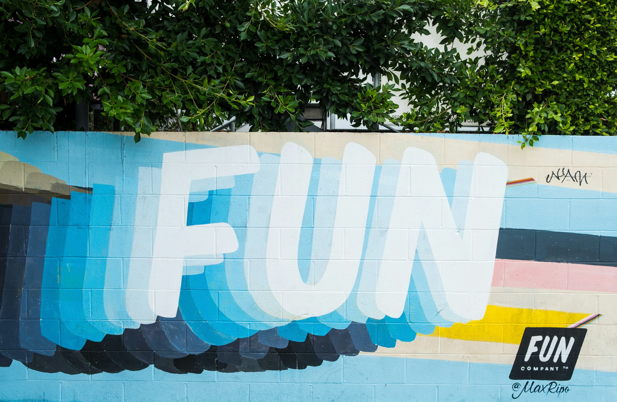 A colorful mural on a cement wall with the word "fun" in big letters.
