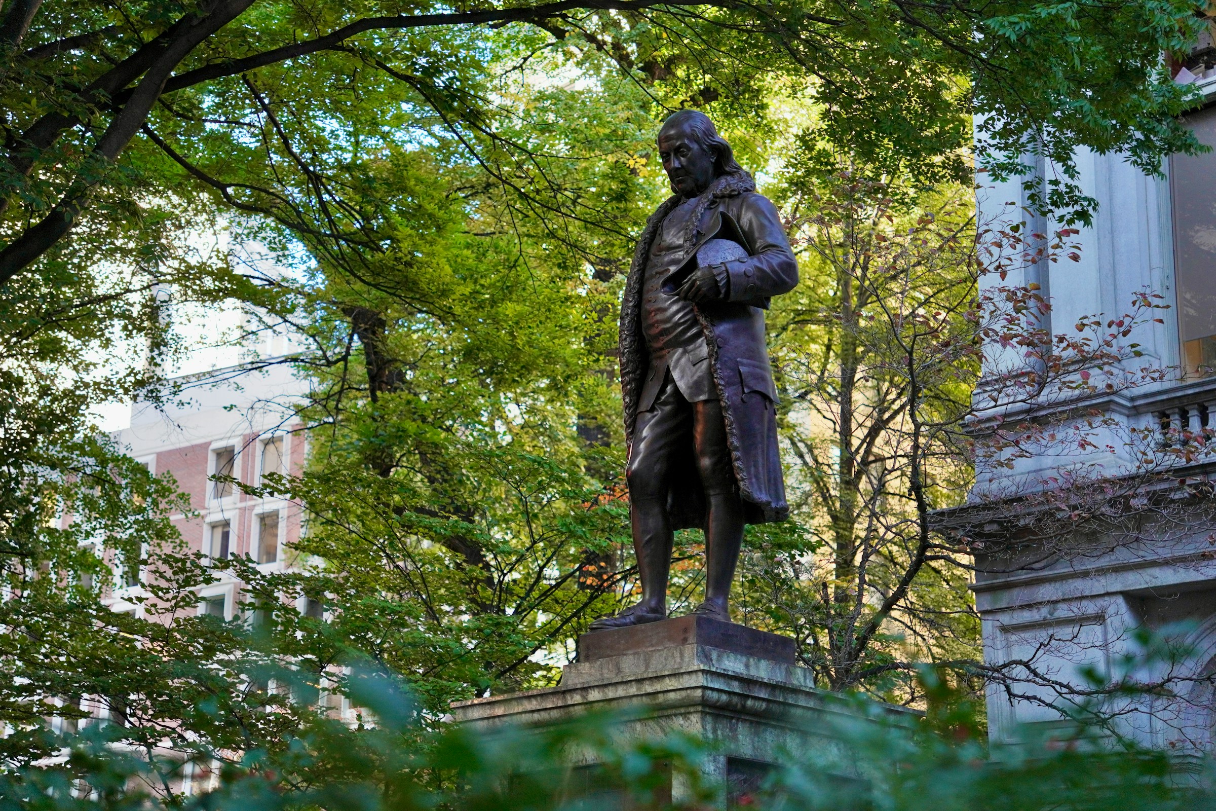 A statue of Benjamin Franklin in a park.