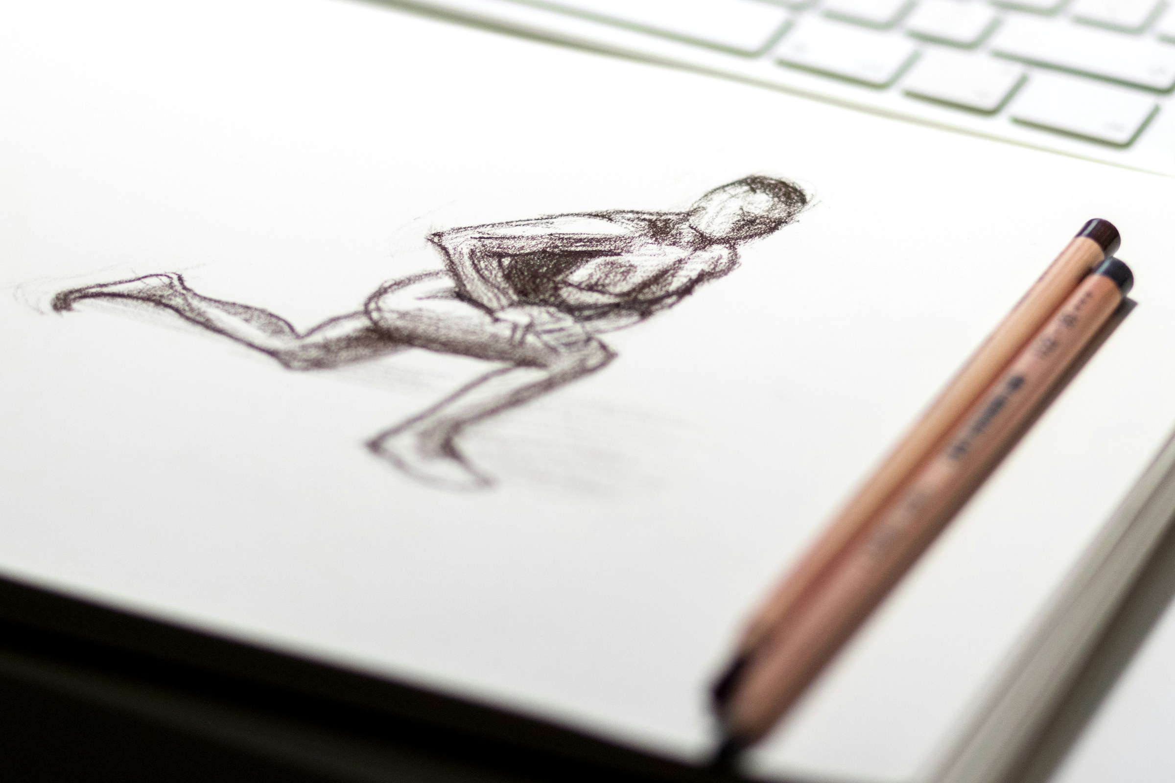 A sketch of a human figure in a runner's lunge sits beside a computer keyboard.