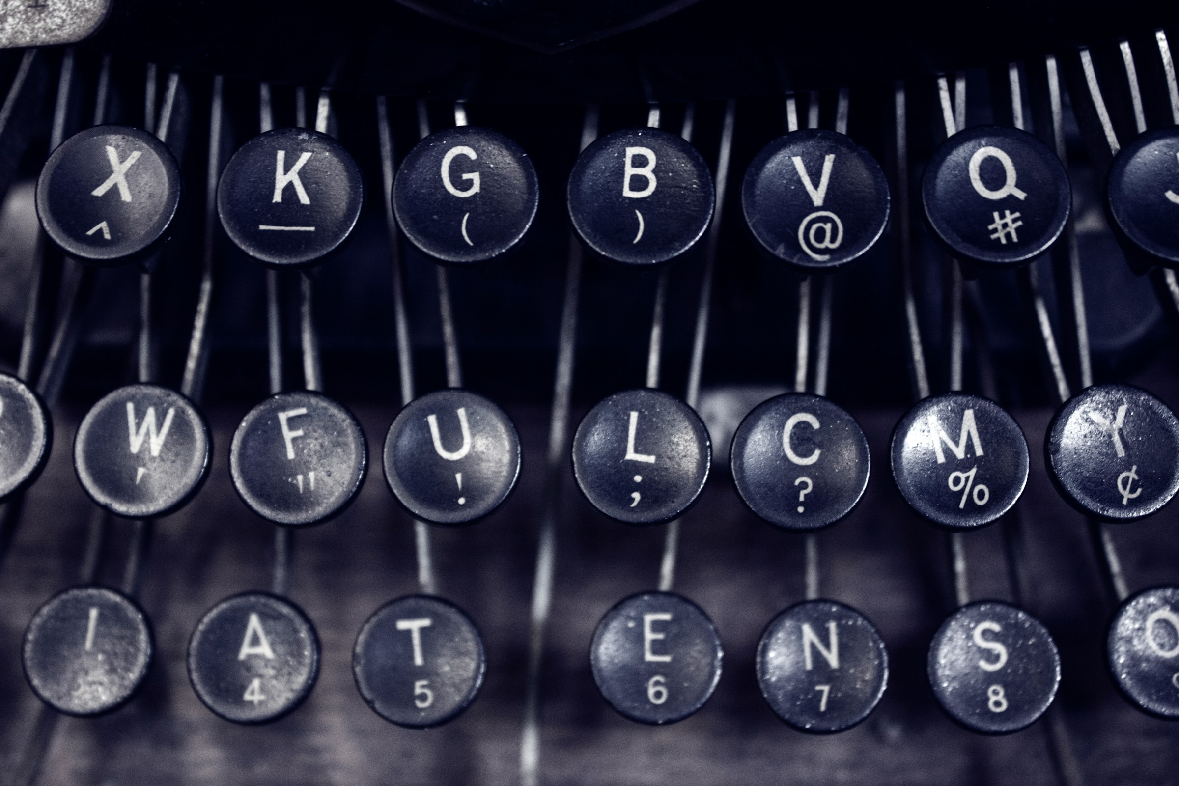 A close-up of round, black, manual typewriter keys.