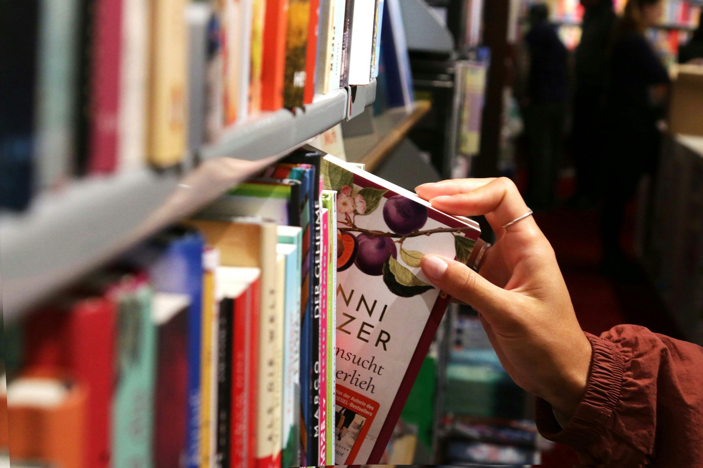 A hand pulls a book off a bookshelf in a store.