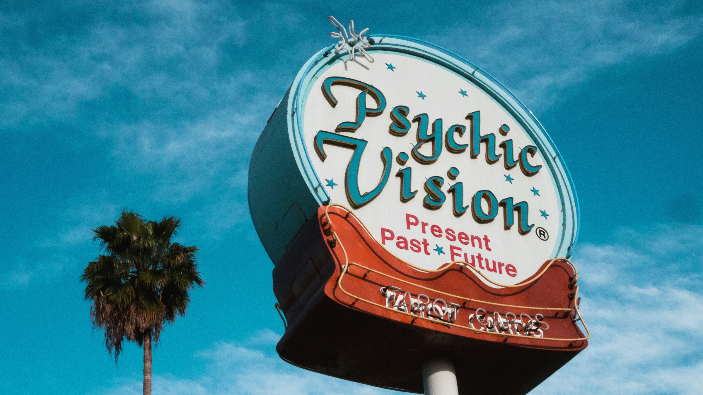A big retro roadside sign reads "Psychic Vision: Past, Present, Future"