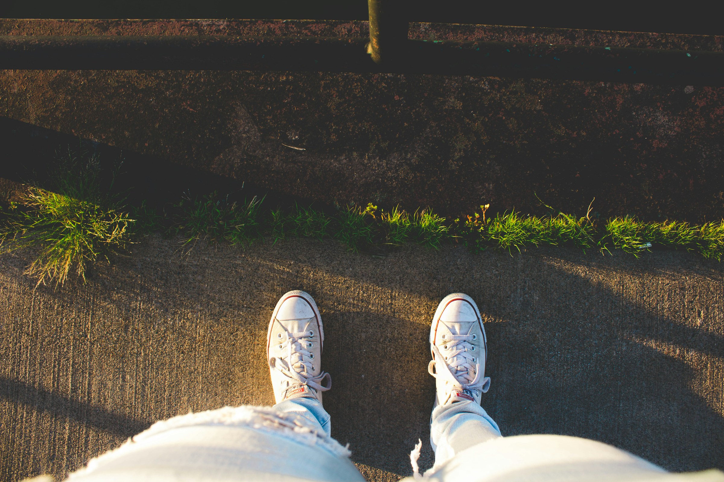 Looking down at someone's light jeans and white sneakers from their point of view.