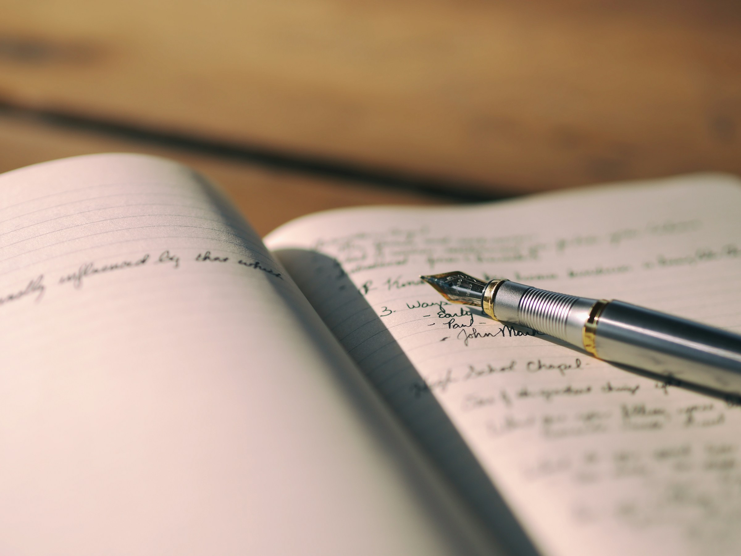 A fountain pen rests on an open notebook.
