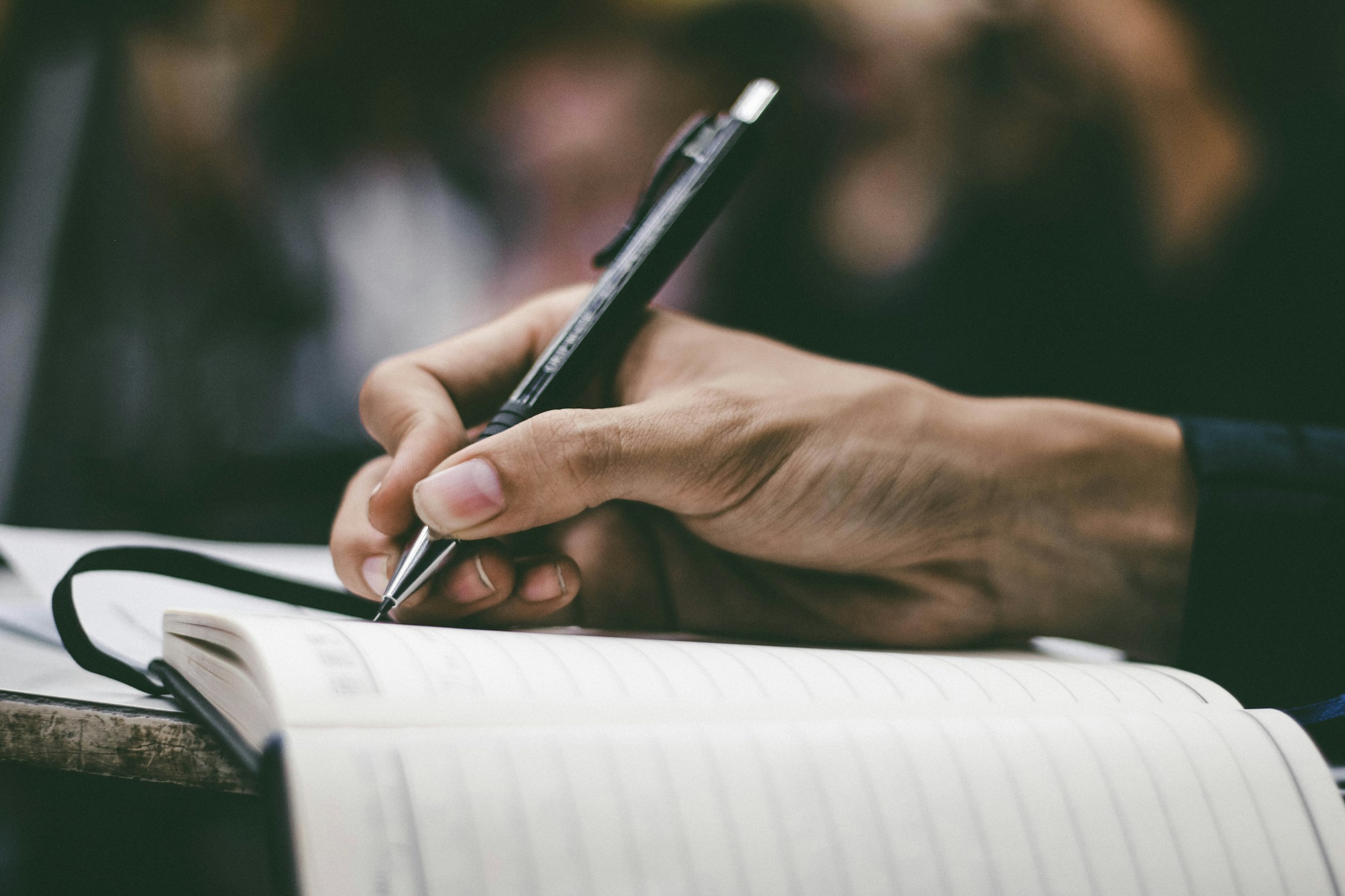 A hand writes in a notebook.