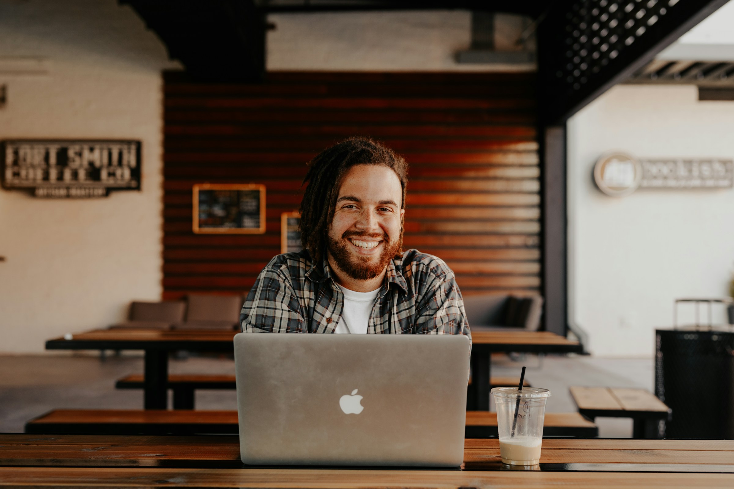A person with a beard smiles over the top of an open laptop.