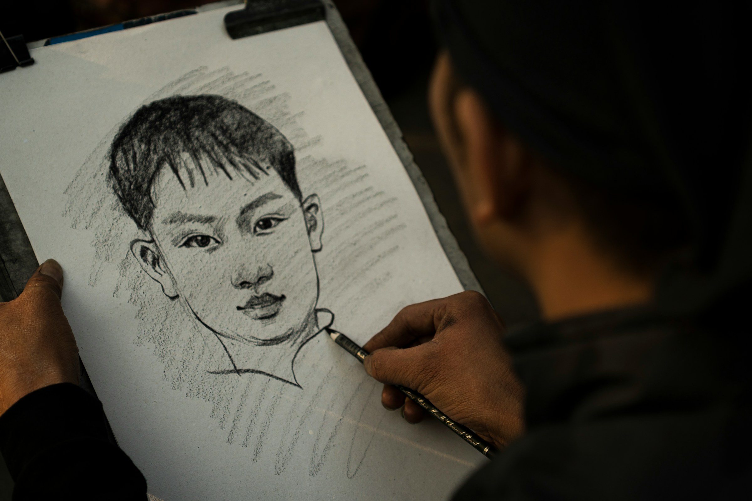 A person draws a face in a sketchbook.
