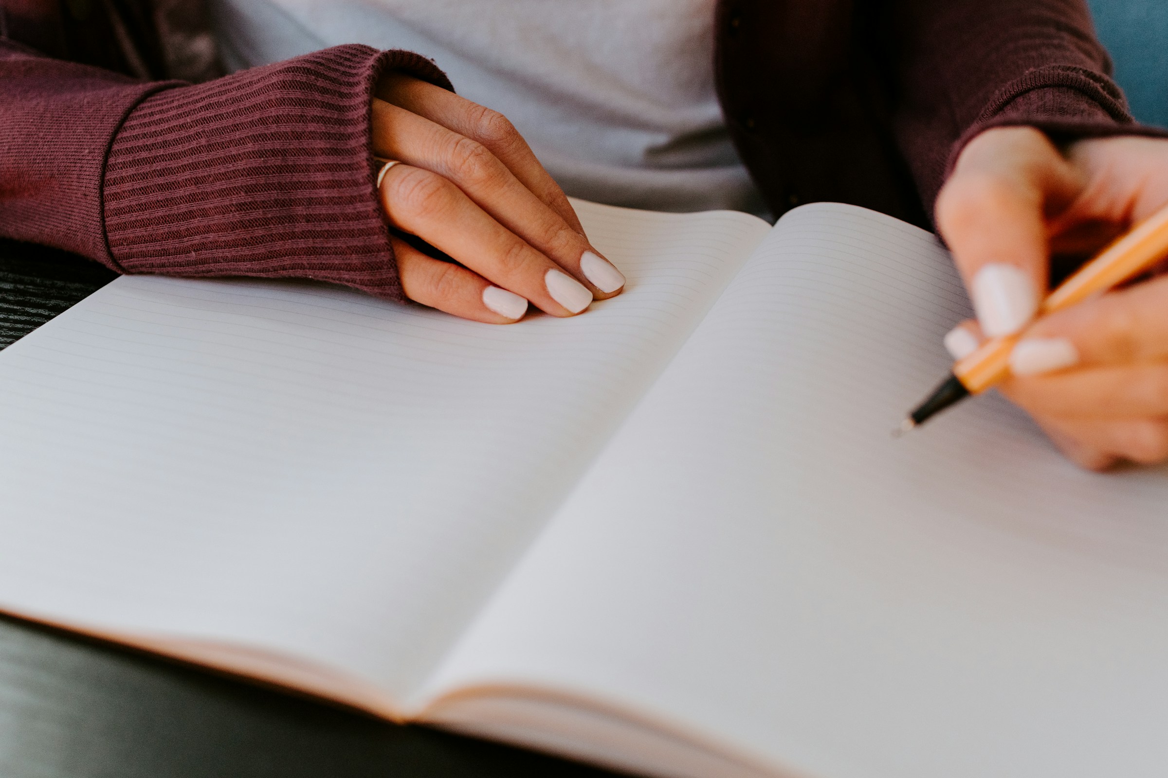A hand writes in an open notebook.