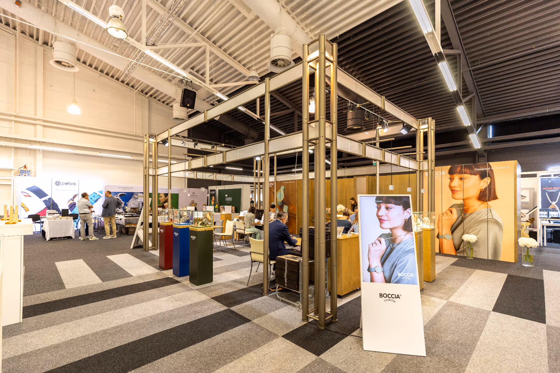 Ausstellung von Autos mit Informationsbannern, einem Laptop auf einem Podium und einem Bildschirm, auf dem ein animiertes Video gezeigt wird, in einem schwach beleuchteten Raum mit violetter und blauer Akzentbeleuchtung.