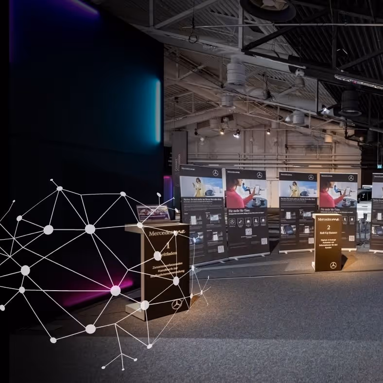 Moderner Ausstellungsraum mit informativen Ständen und digitalen Displays unter industrieller Deckenbeleuchtung.