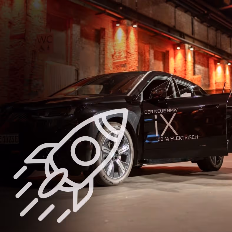 Schwarzes Elektroauto, das in einem Innenraum mit roter Umgebungsbeleuchtung vor Backsteinwänden geparkt ist.