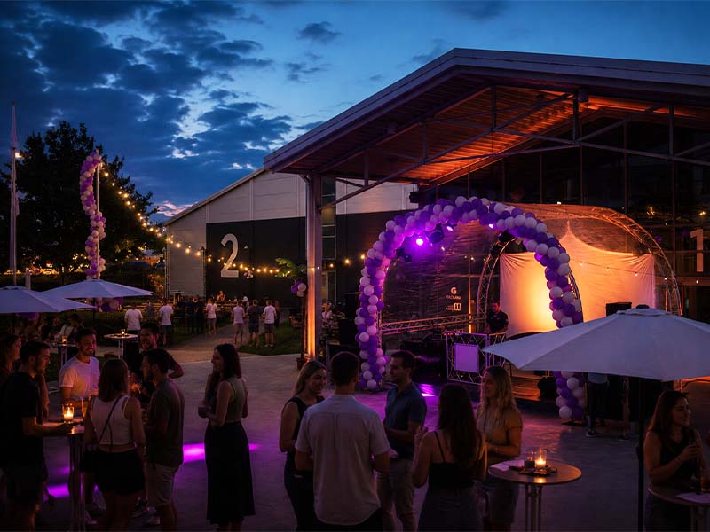 Menschen feiern abends bei einer Party mit Lichterketten und Ballonbögen auf dem Globana Event Campus.