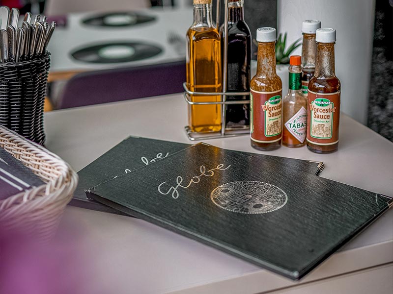 Tisch in einem Restaurant mit zwei Menüs, Öl- und Worcestersaucen sowie Tabasco-Sauce.