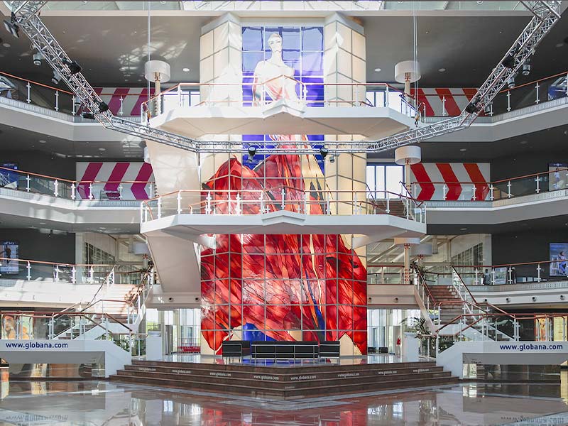 Moderne mehrstöckige Halle mit zentraler Treppe und großer roter Kunstinstallation an der Wand.