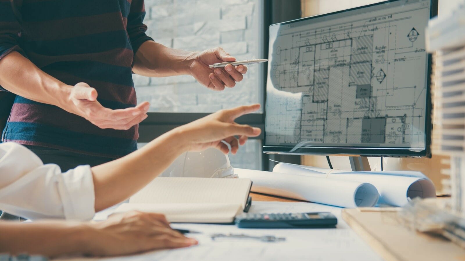 The picture of 2 people discussing the construction model on monitor