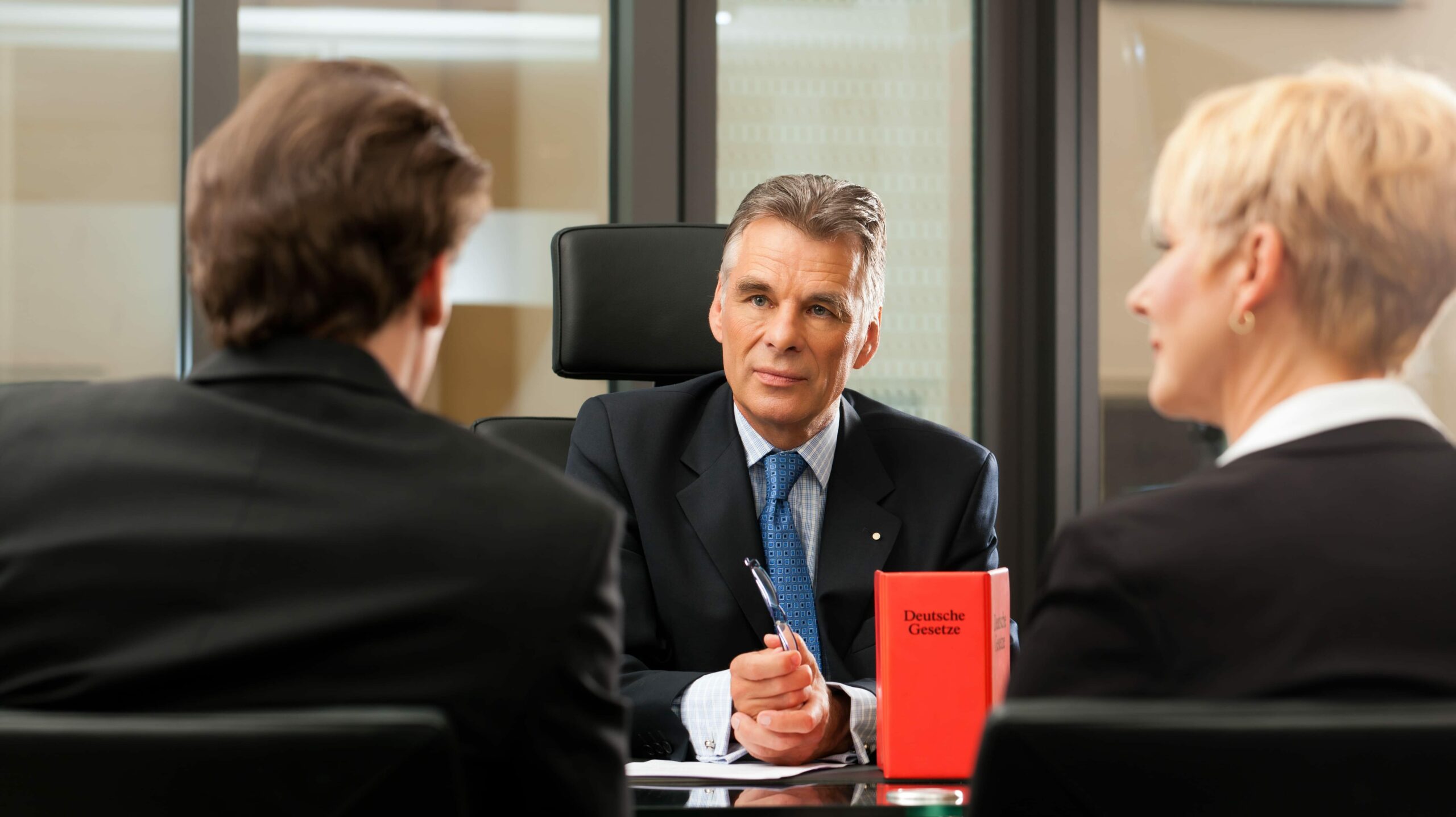 The picture of a man sitting across two men in a meeting