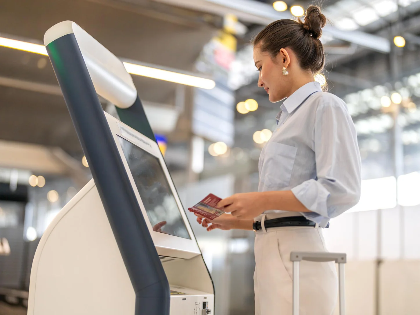 Passenger using an automated self-service check-in kiosk at an airport