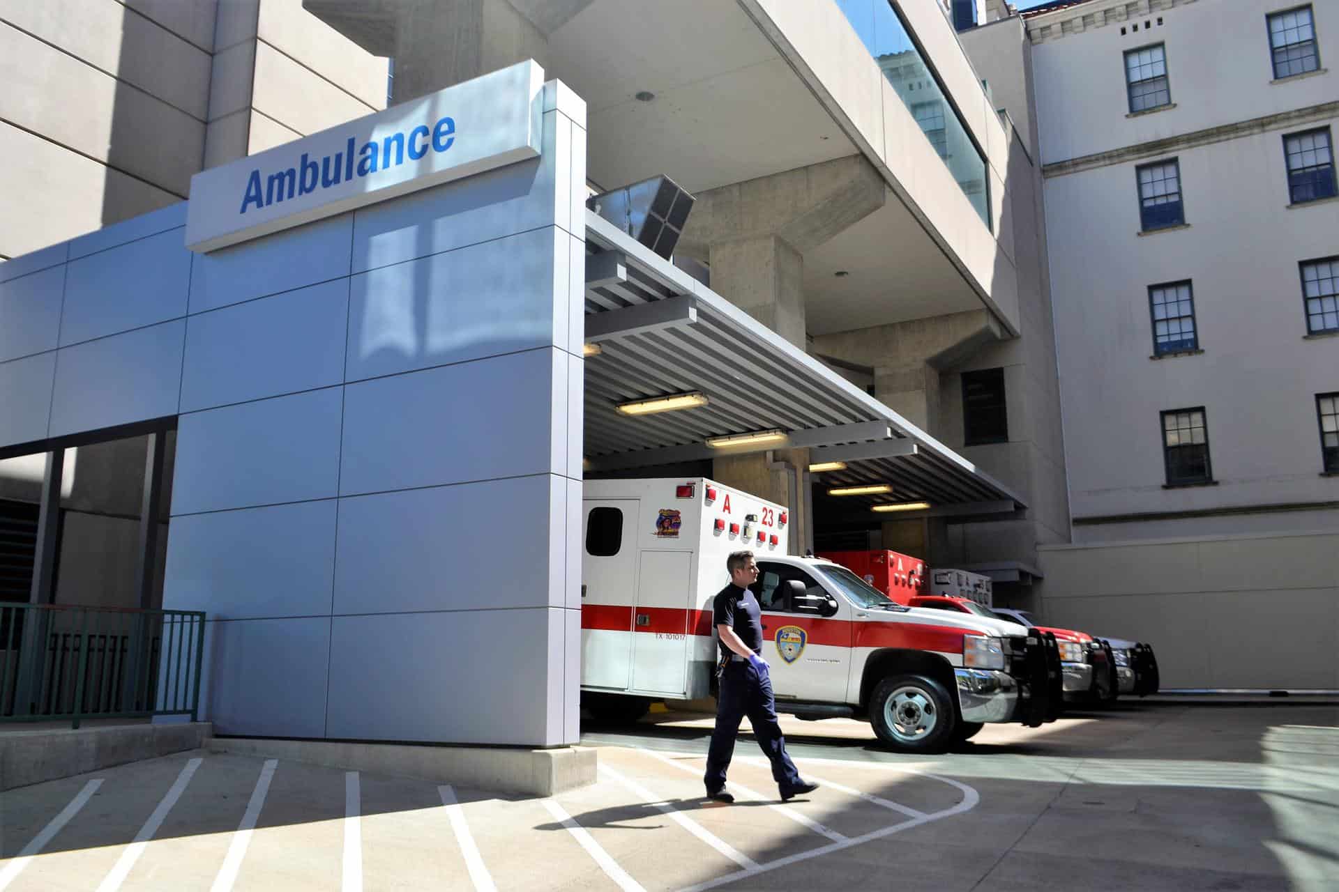 hospital worker walking through ambulance section of the hospital parking lot