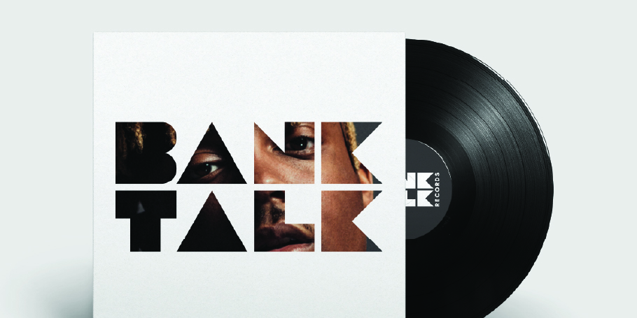 Vinyl record partially out of a white sleeve with the words 'BANK TALK' cut out, showing a man's face behind the letters.