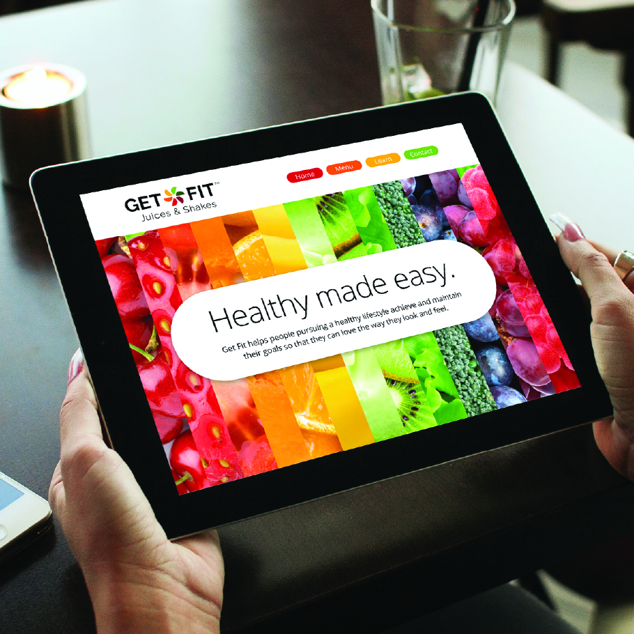 Person holding a tablet displaying a colorful website for Get Fit Juices & Shakes with the slogan 'Healthy made easy.'