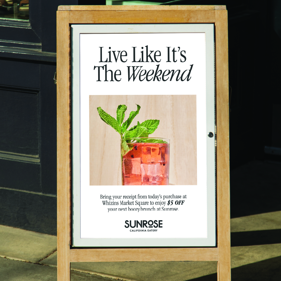 Outdoor sign displaying a red cocktail with mint and text offering $5 off next boozy brunch at Sunrose 