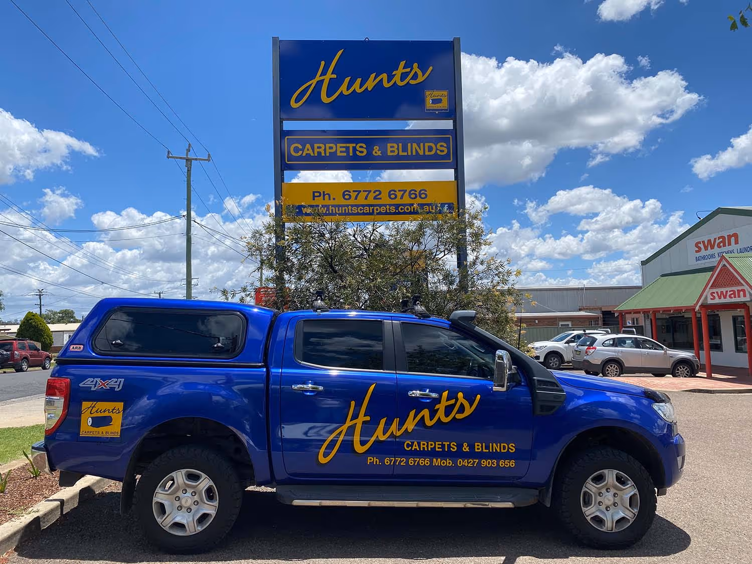 Blue car with branding of Hunts carpets and blinds 