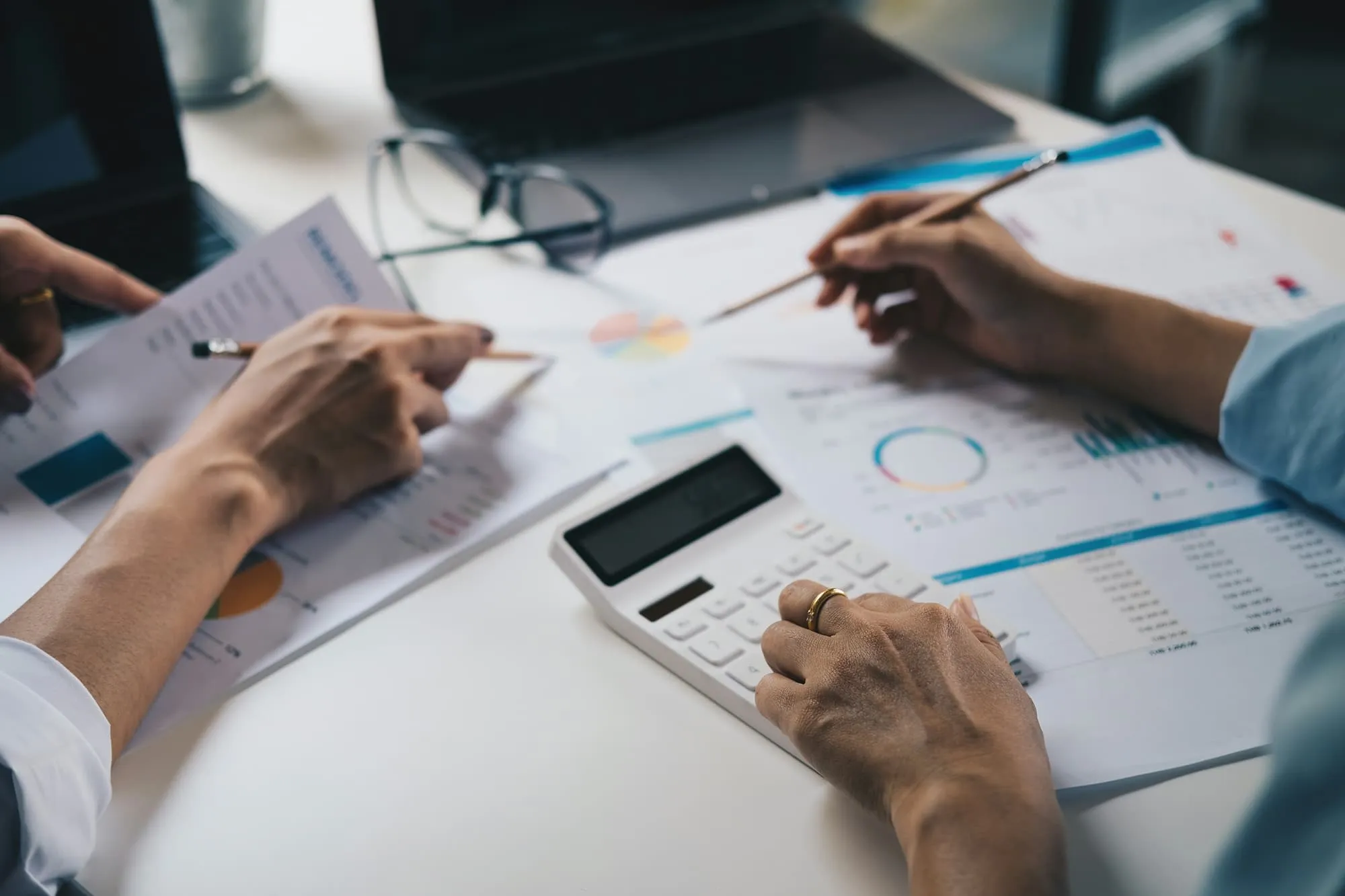 A couple of people sitting at a table with a calculator.