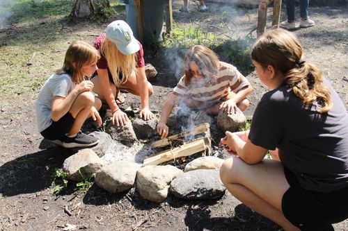 Campers cook bannock on a stick over a fire.