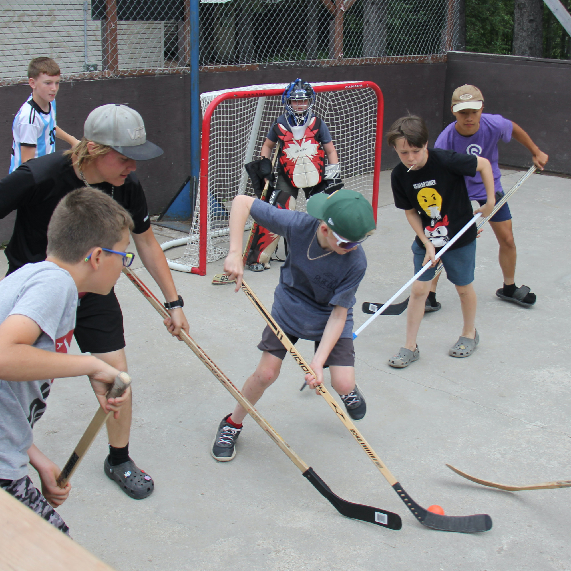 Campers play ball hockey on a wet court.