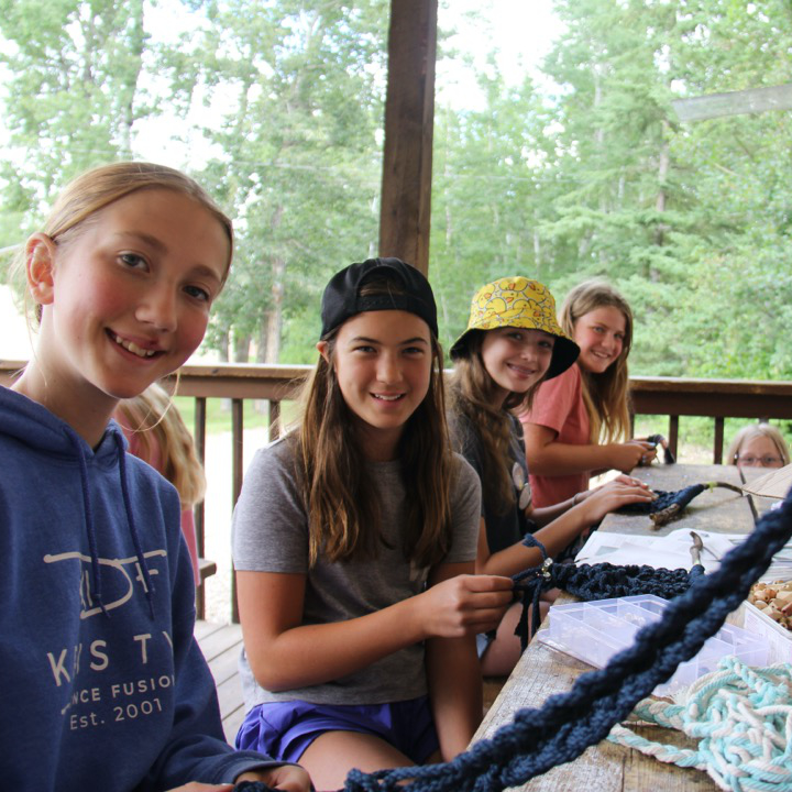 Campers sit at a long table making crafts.