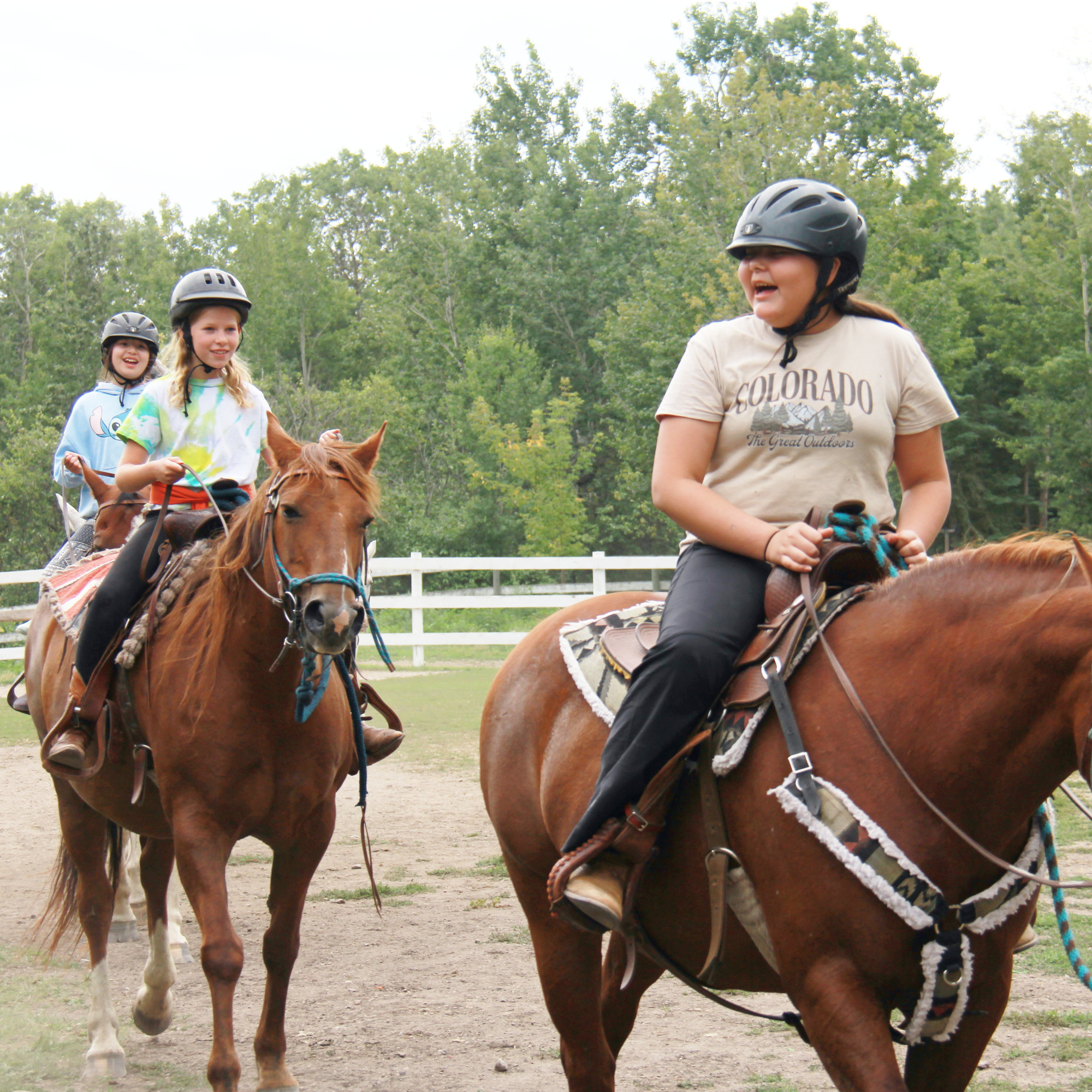 A girl on a horse gets sprayed by a hose.