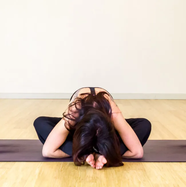 A female in butterfly yin yoga pose on a yoga mat