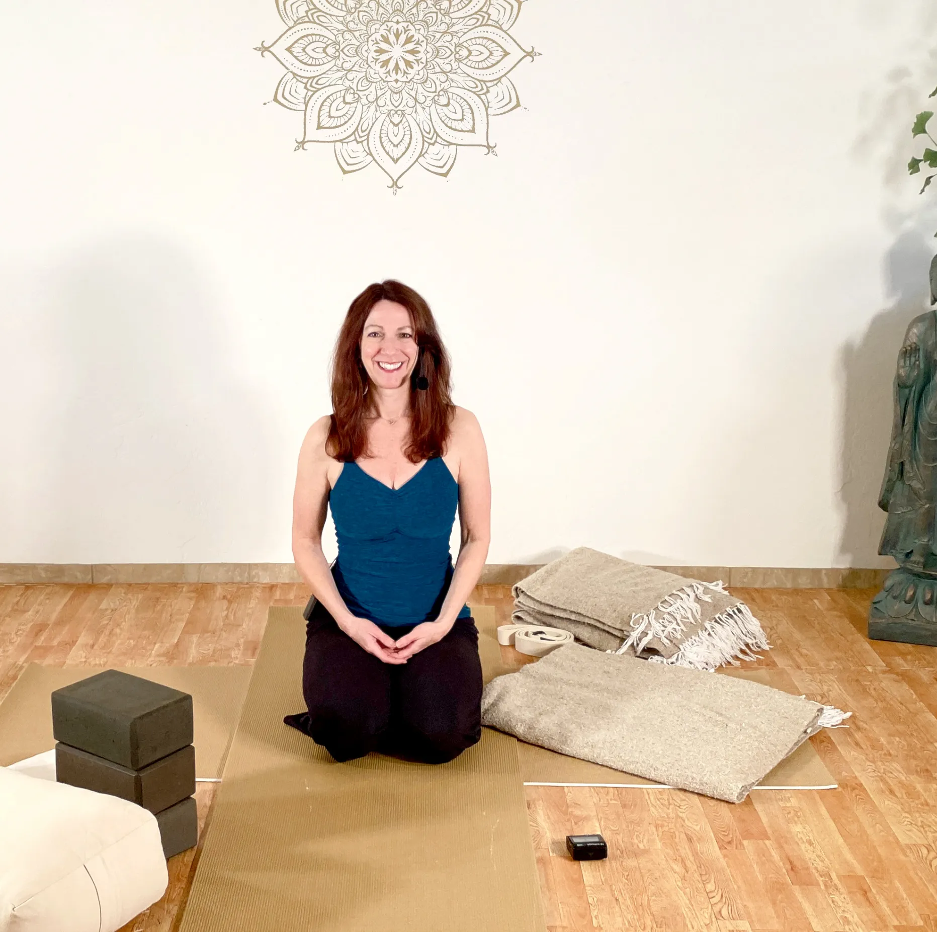 A woman sitting on a yoga mat smiling 