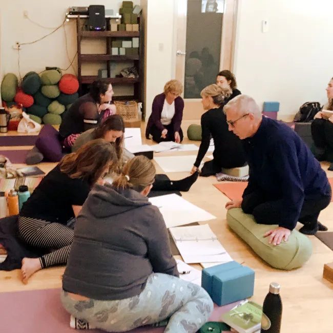 Students working in small groups in a yoga studio