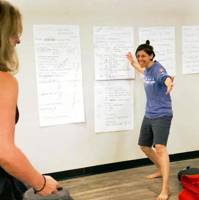 Student smiling and presenting a yoga sequence to another student