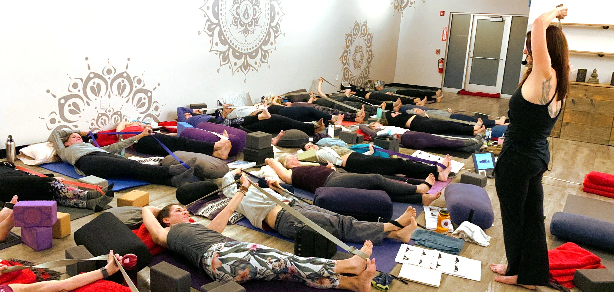 Teacher teaching Yin yoga pose to students lying on the floor