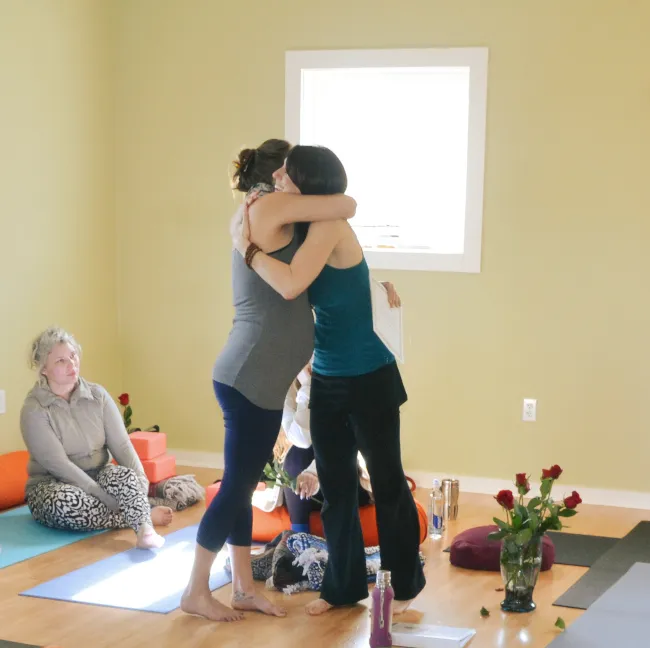 Teacher and student hugging in a circle of students