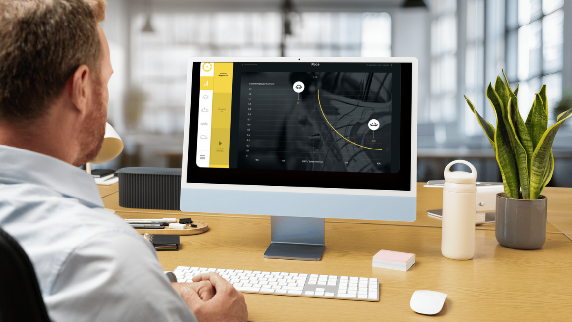 Man in light blue shirt sitting at a desk looking at a computer screen displaying a financial graph with yellow highlights.