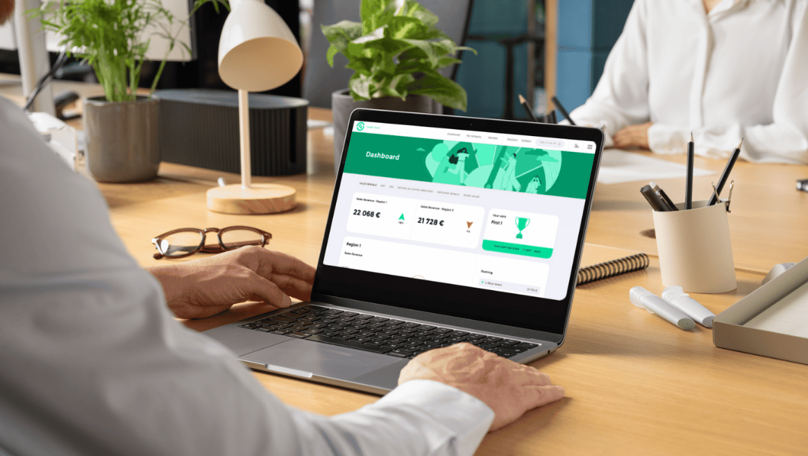 Person using a laptop showing a dashboard of the Business Sustainability Challenge with figures and a trophy icon on a wooden office desk.