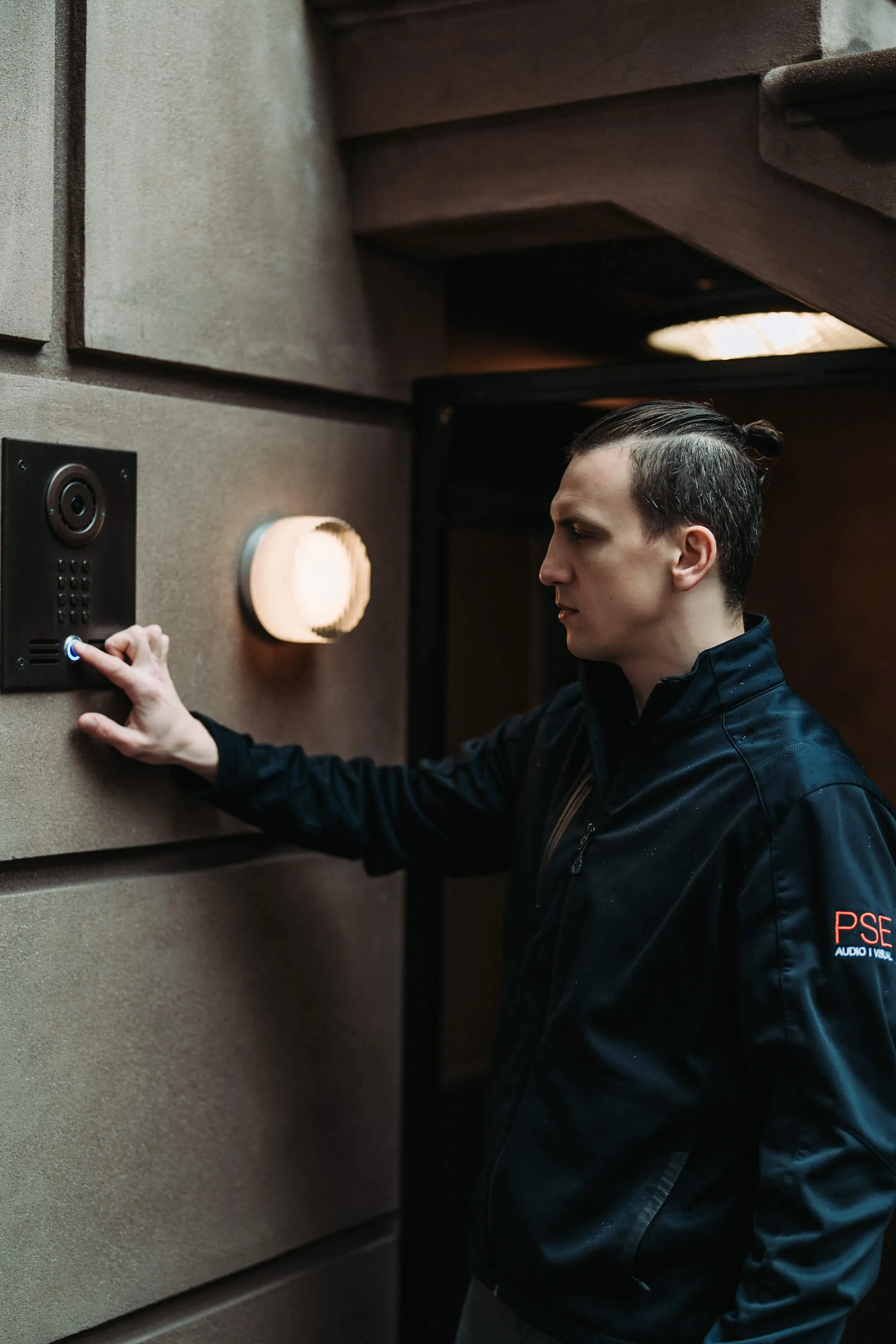 PSE technician testing a door entry keypad beside a door in a New York home