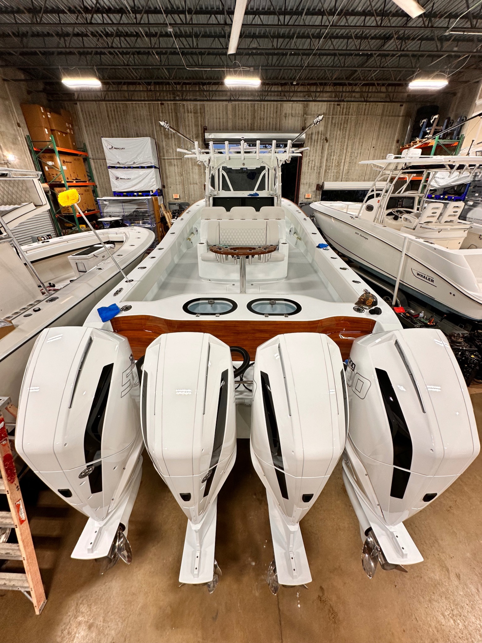 Stern view of a center-console boat with four white outboard engines in the workshop