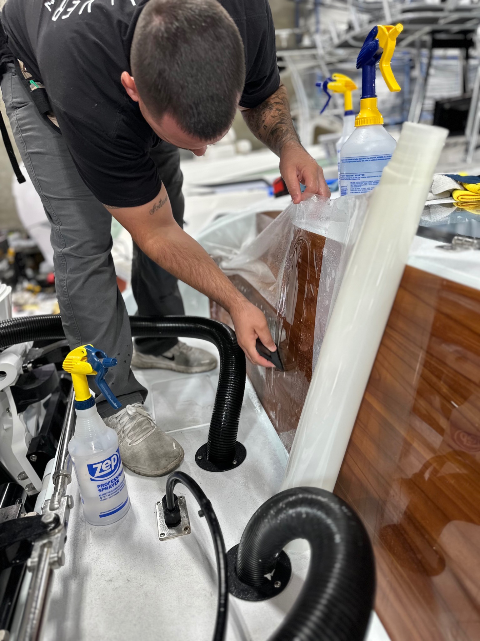 Technician fitting protective film to an interior wood surface aboard a boat