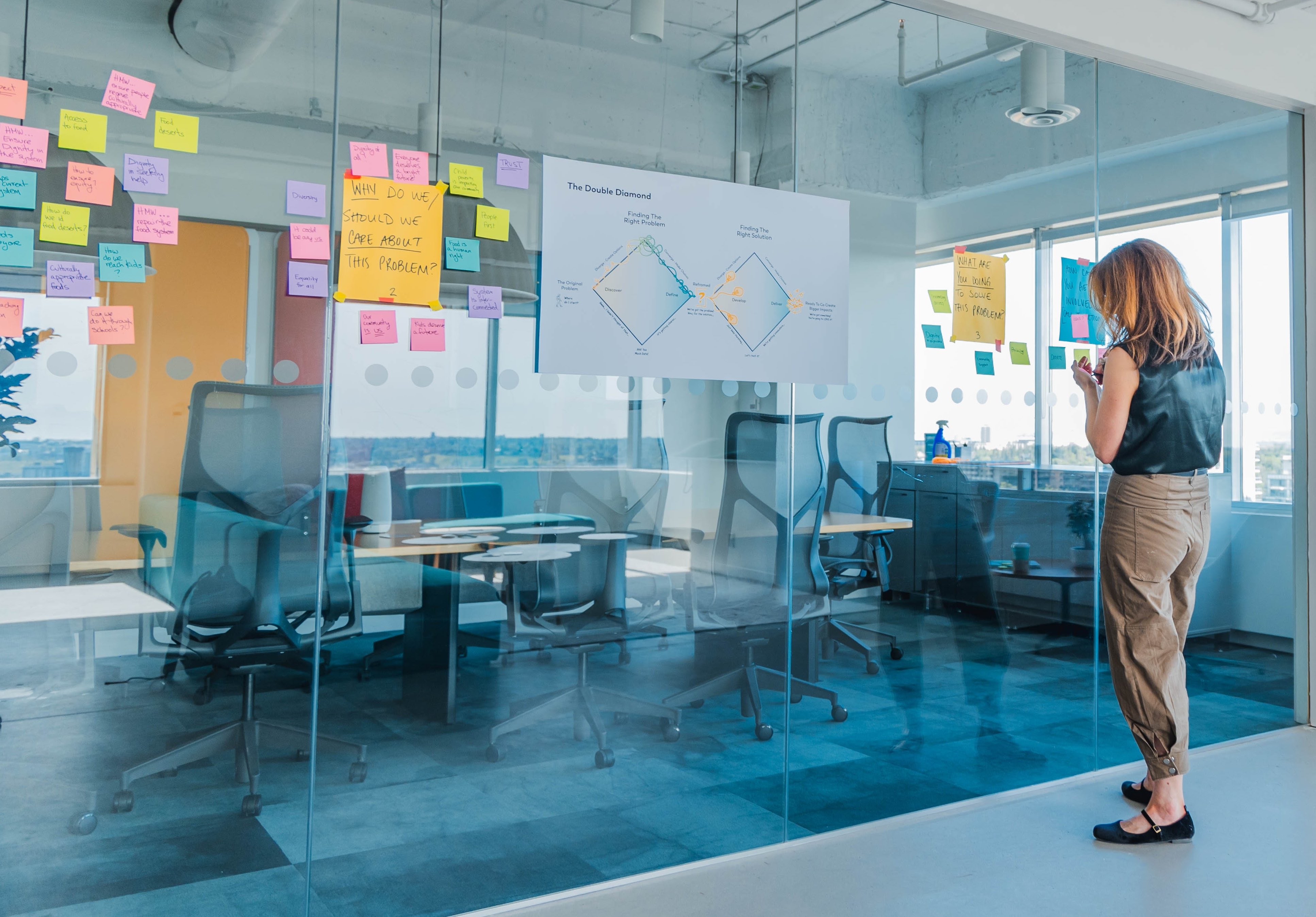 A woman looking at a wall of sticky notes and information. 