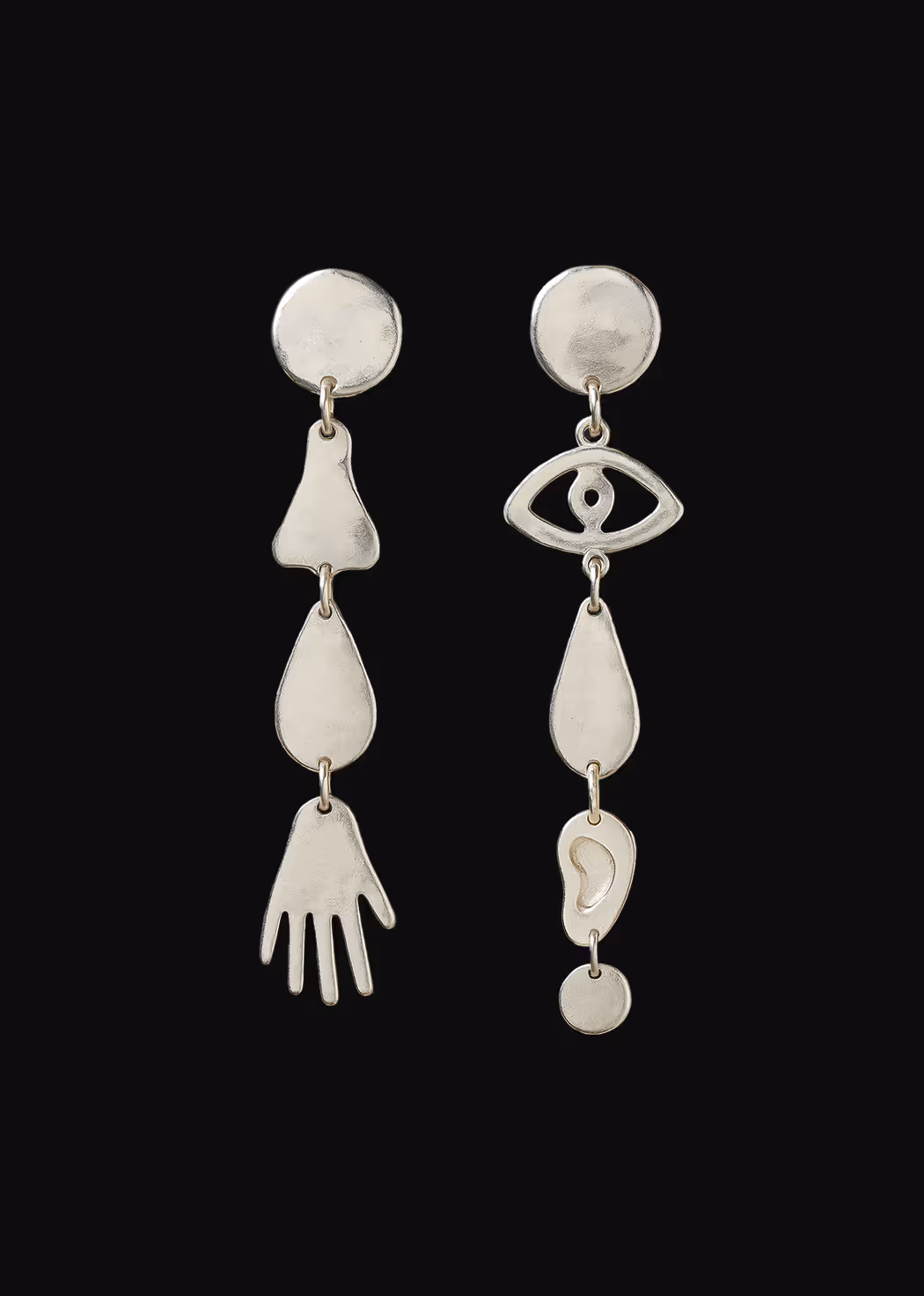Asymmetrical silver dangling earrings with abstract shapes including a hand and eye shape.