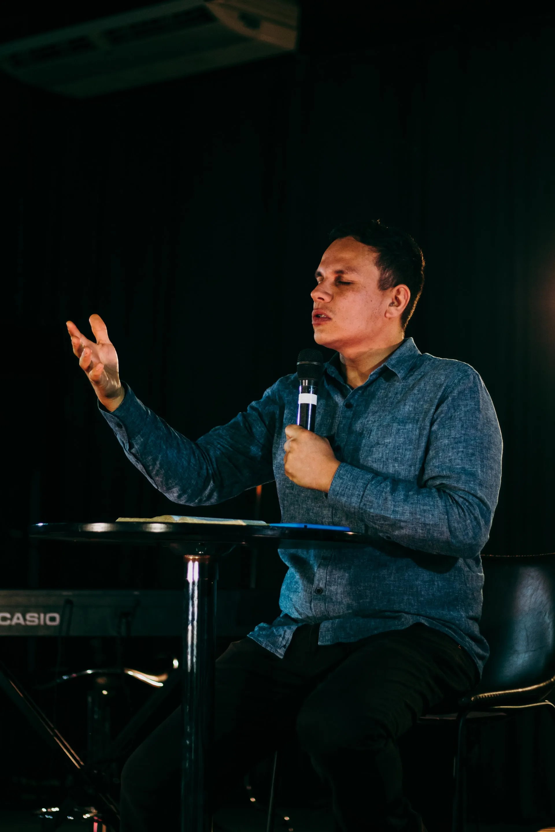 A photo of a man wearing a blue long sleeve and holding a microphone at Jesus Pattern