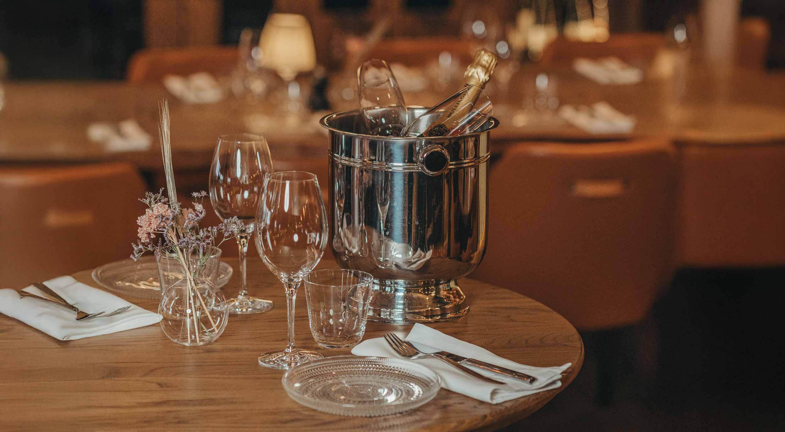 Fint dukat bord med glas, bestick, en vas med blommor och en kall champagneflaska i en ishink.