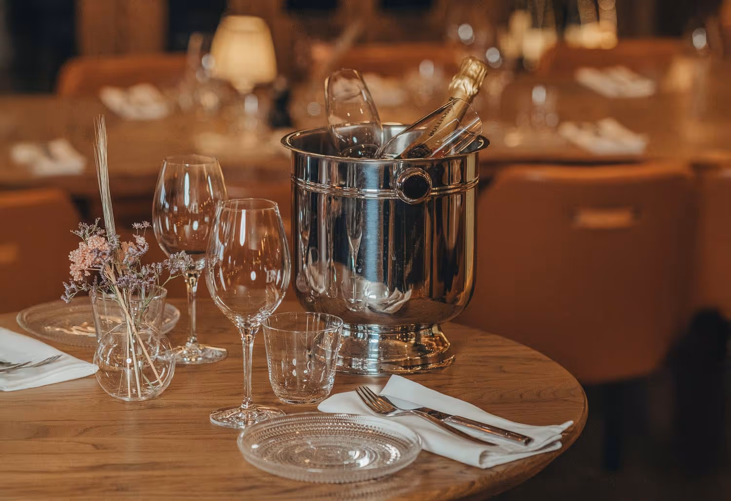 Fint dukat bord med glas, bestick, en vas med blommor och en kall champagneflaska i en ishink.