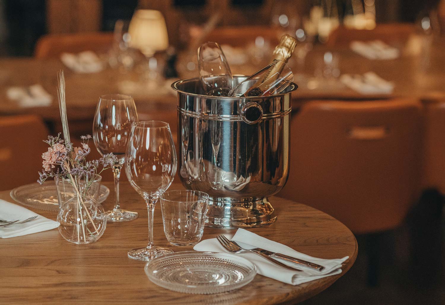 Fint dukat bord med glas, bestick, en vas med blommor och en kall champagneflaska i en ishink.