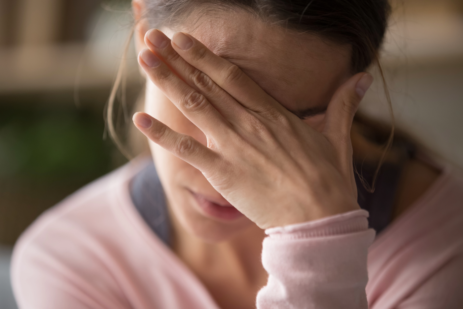 Woman covering face with hand, appearing distressed.