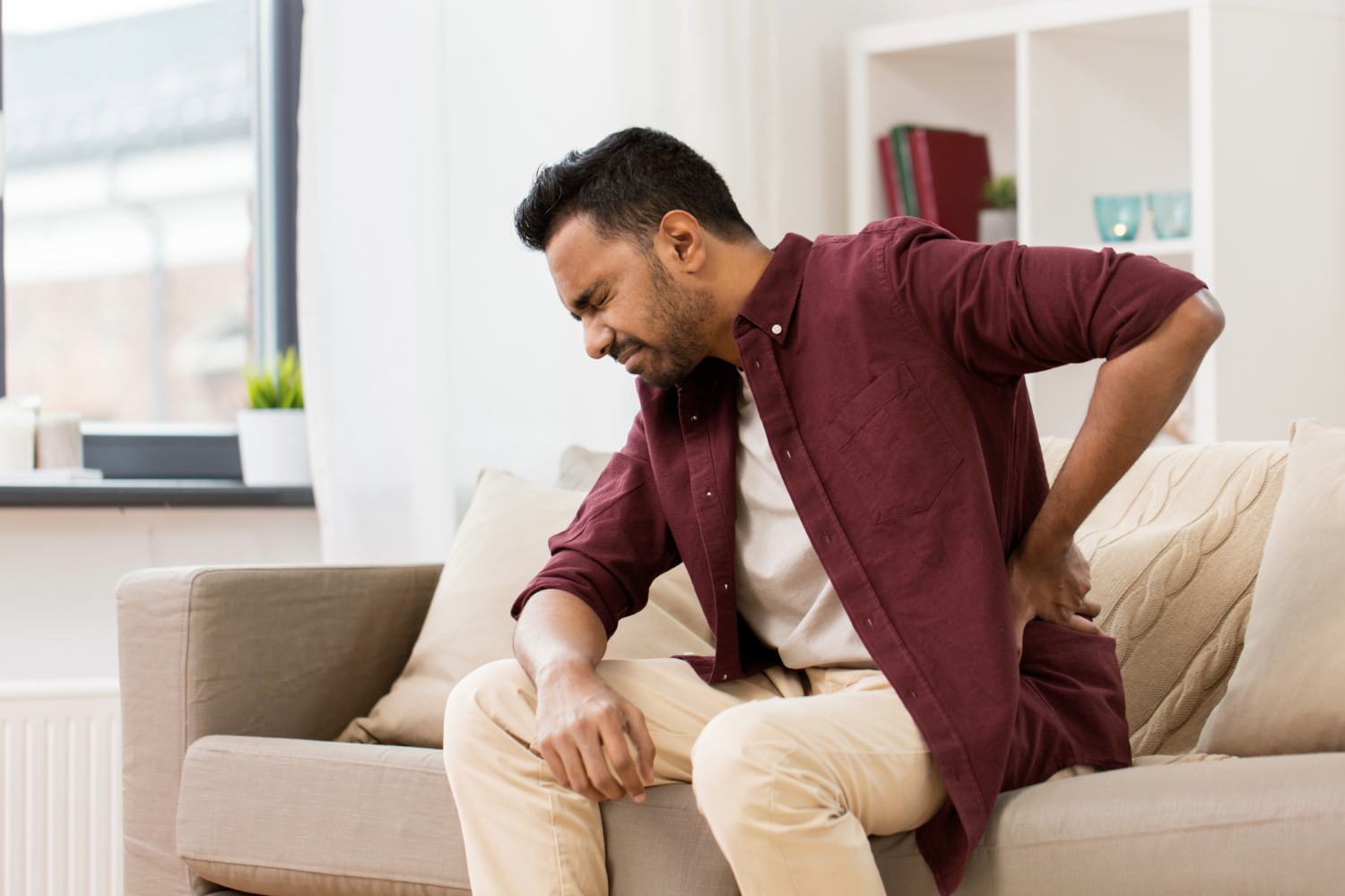 Man with back pain sitting on couch